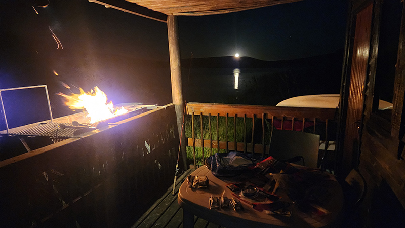 Braai smoke rising from the Damhuis deck as the moon rises over the dam